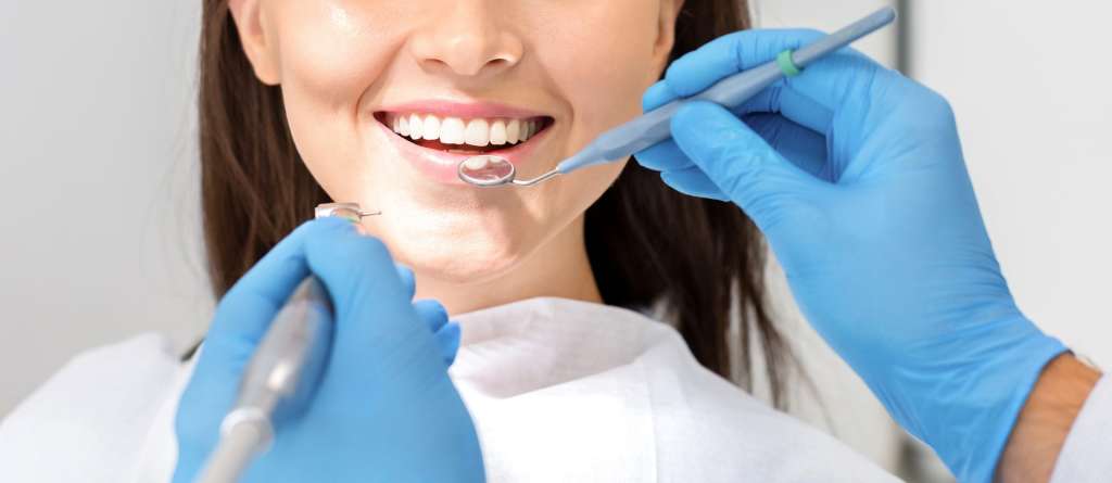 Dentist polishing a smiling patient's teeth during a routine check-up