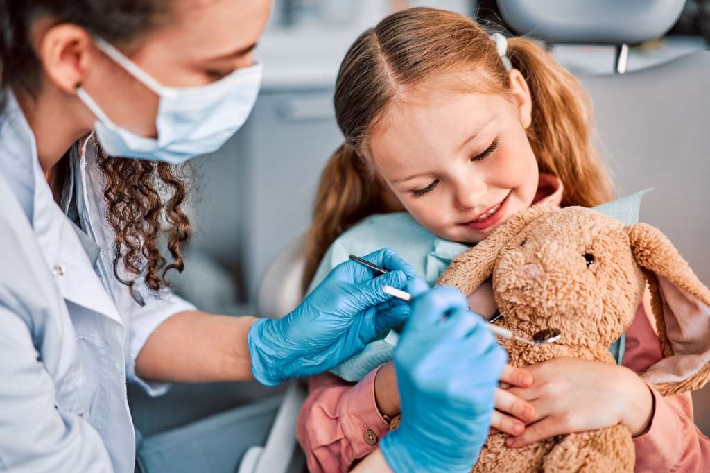 Dentist introducing a young child to dental instruments using a toy